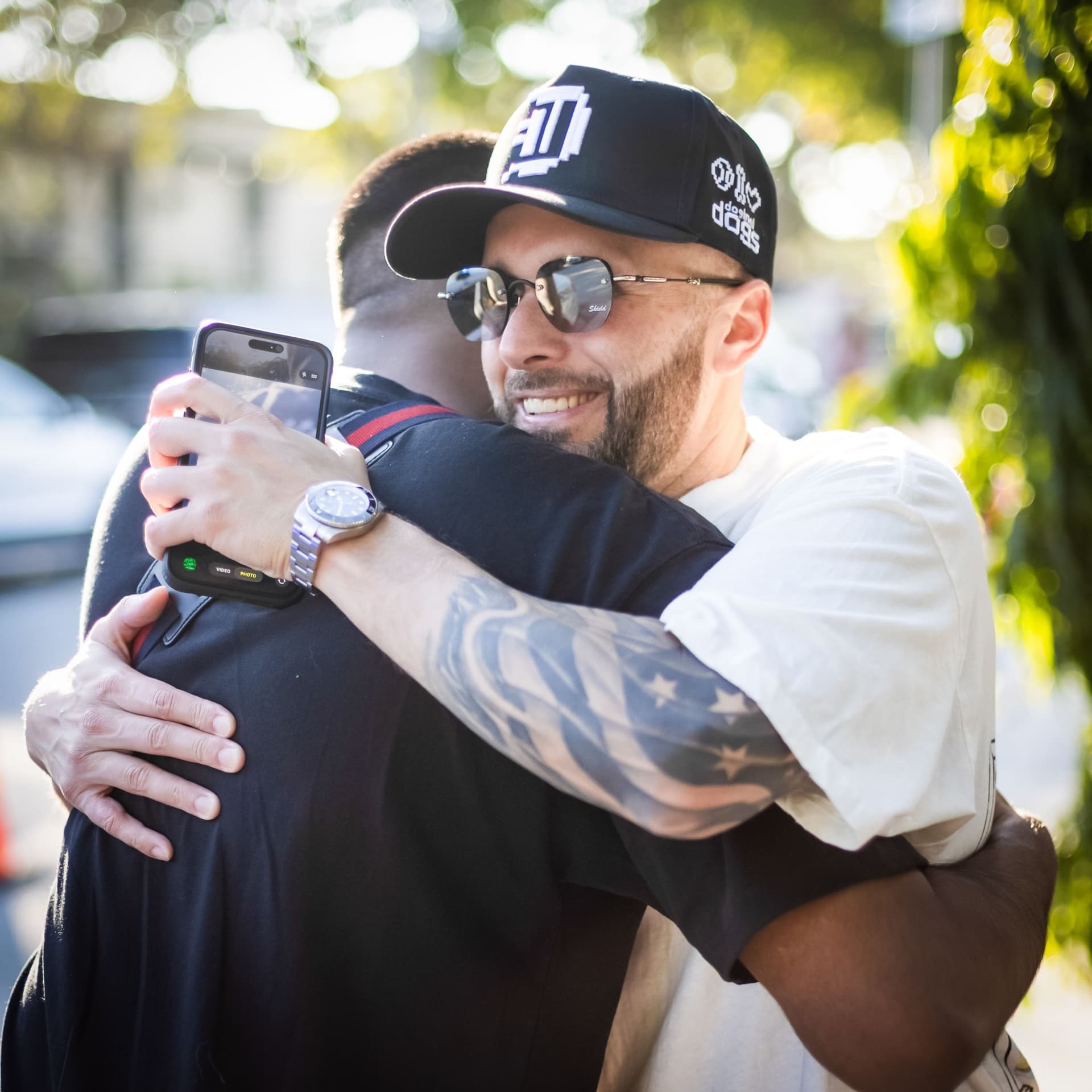 Damien Galvin with the community Damien Galvin (Shield / @Shieldmetax) in a Doginal Dogs cap hugging someone outdoors