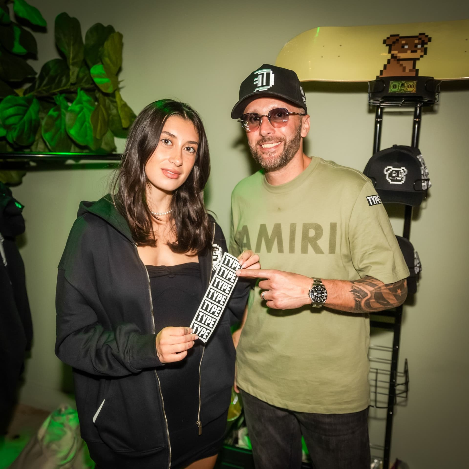 Damien Galvin at a merch table Damien Galvin (Shield / @Shieldmetax) in a cap and sunglasses holding a TYPE sticker at a merch table